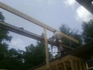 Carpenter setting a ridge beam over a new addition frame — Ice Dam Removal by Roofing Brothers in Eureka
