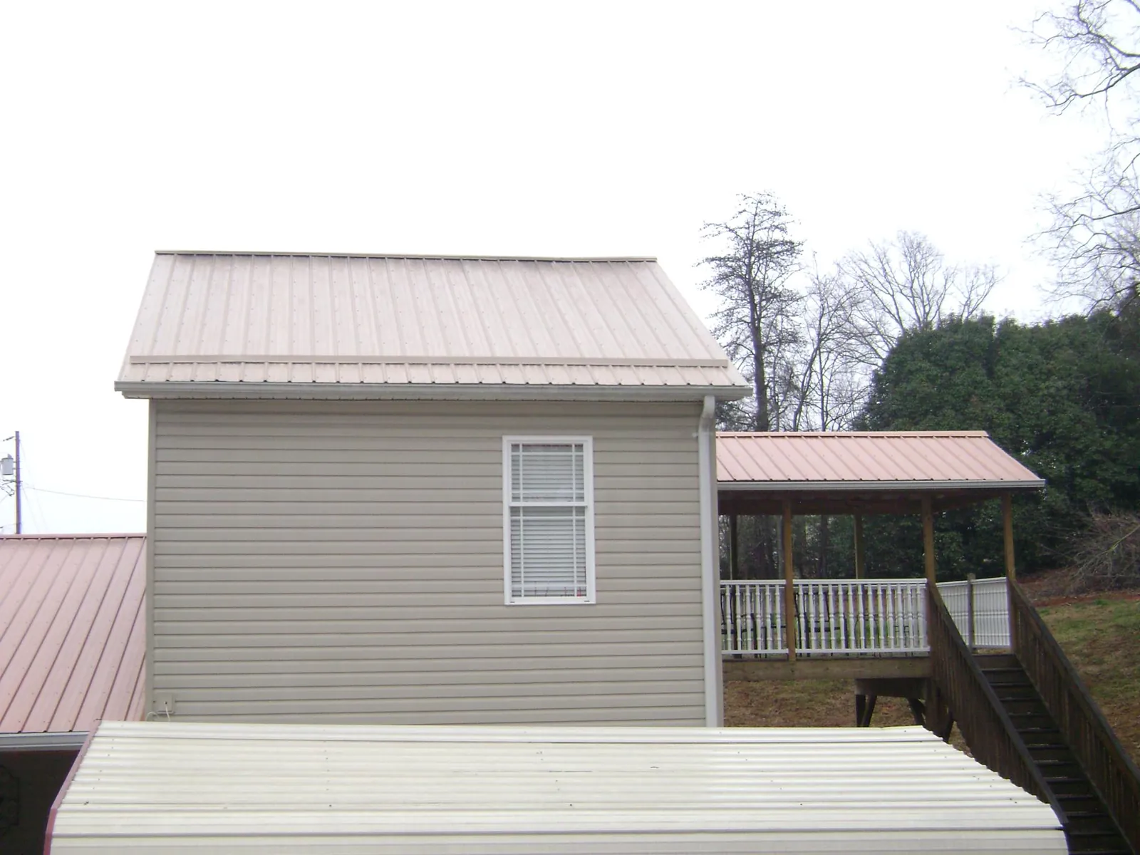 Tan metal roofs on a two story addition and attached porch, from a Roof Replacement job in Eureka