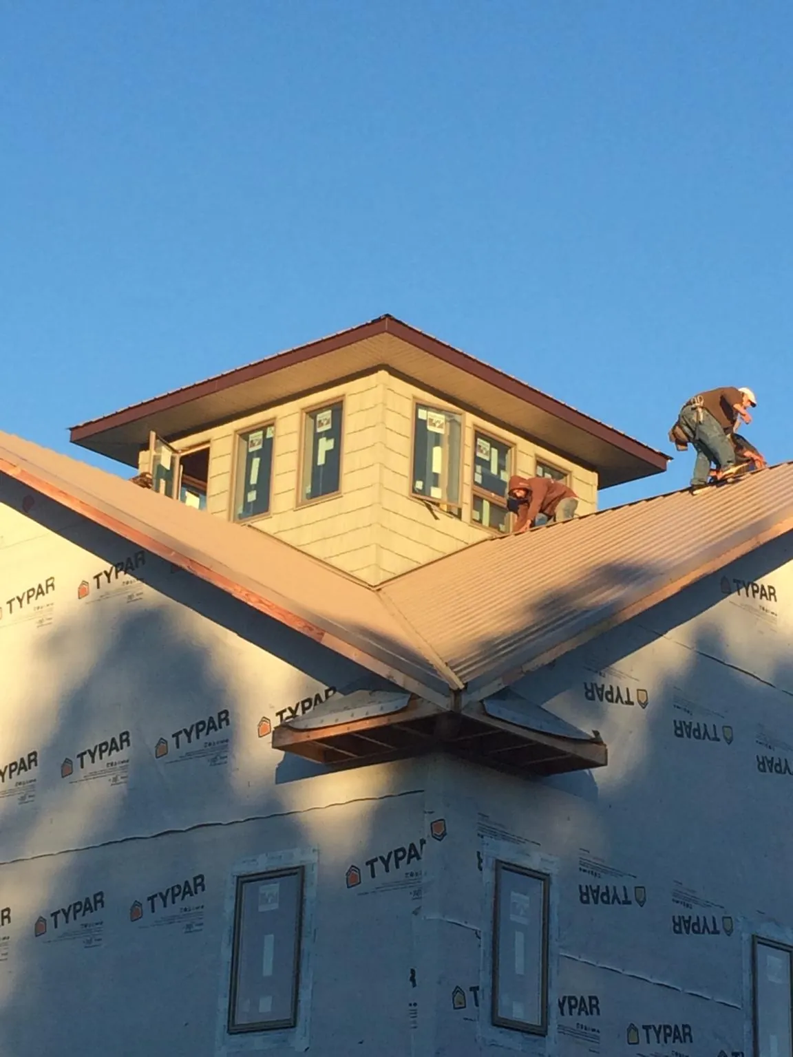 Roofers working around a rooftop cupola on a new metal roof at sunset — Roof Waterproofing in Eureka by Roofing Brothers